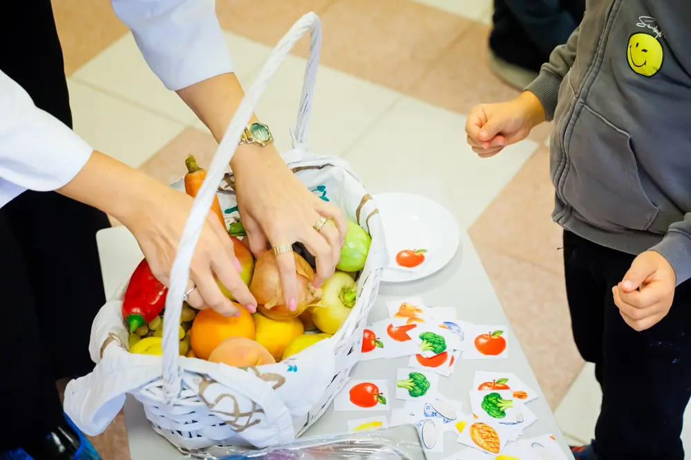 Mâinile Elenei Pădurariu în coșul cu fructe, lângă stickerele cu alimente